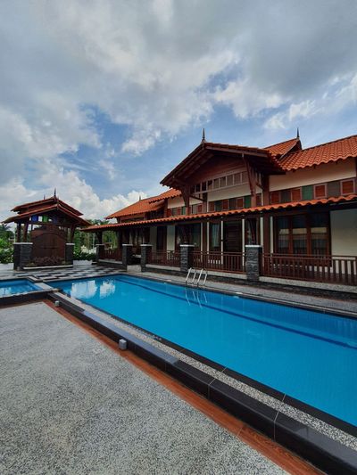 Kolam biru di hadapan bumbung dan pintu kayu Anjung Dahlia