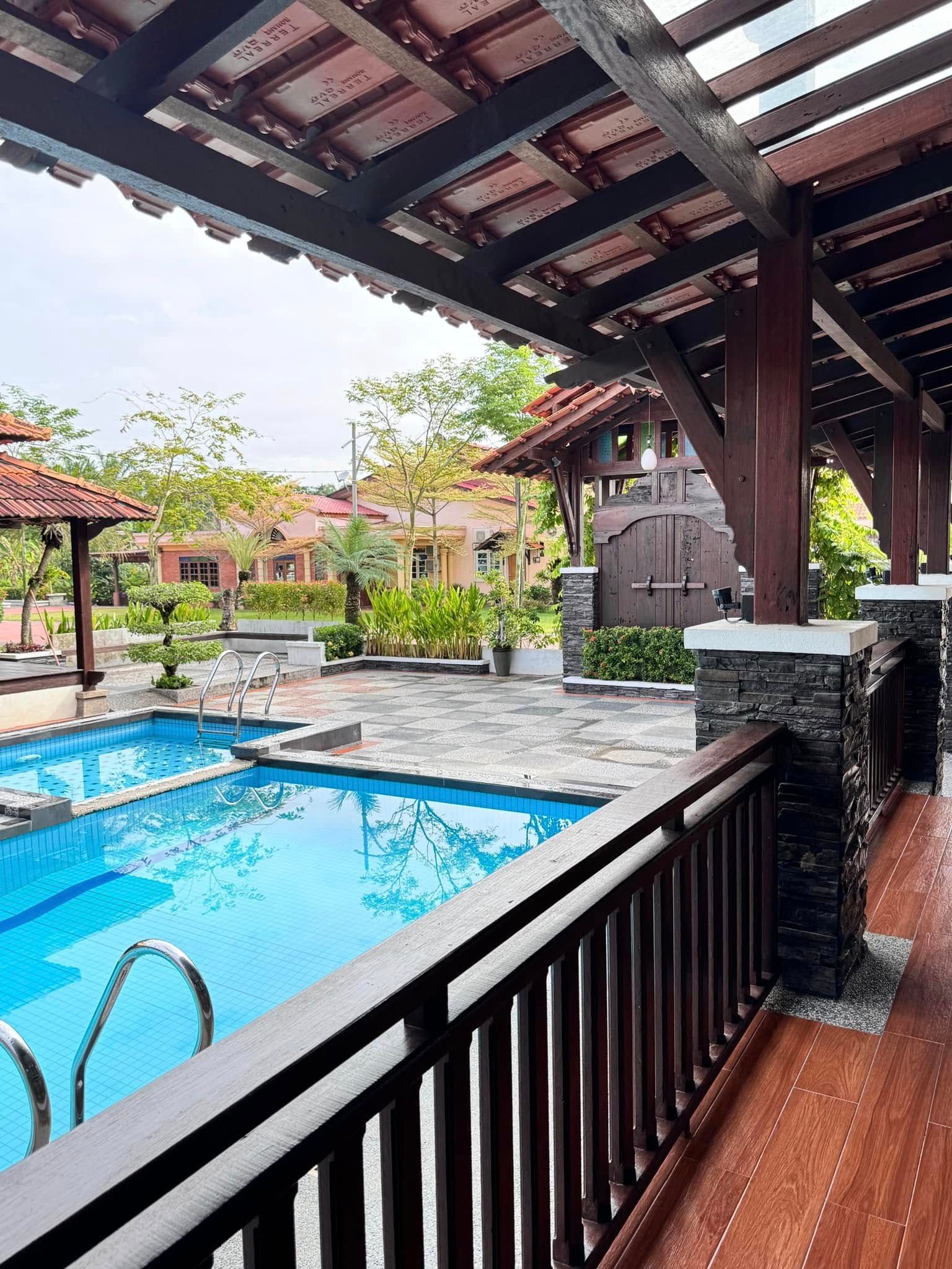 The pool and the chequered courtyard seen from the tiled timber verandah, with the timber gateway beyond.