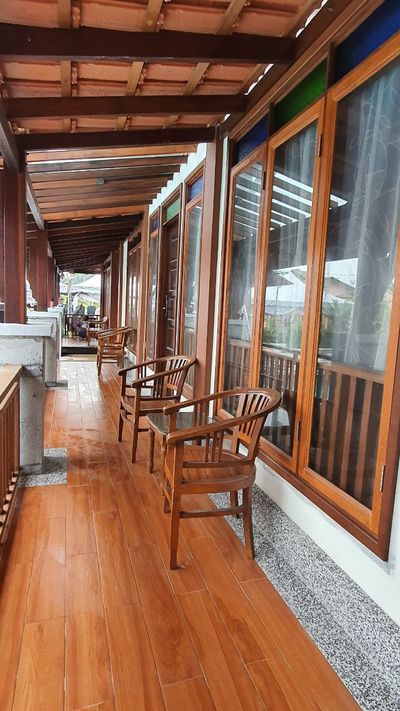 Deretan kerusi dan tingkap di sepanjang anjung kayu berbumbung