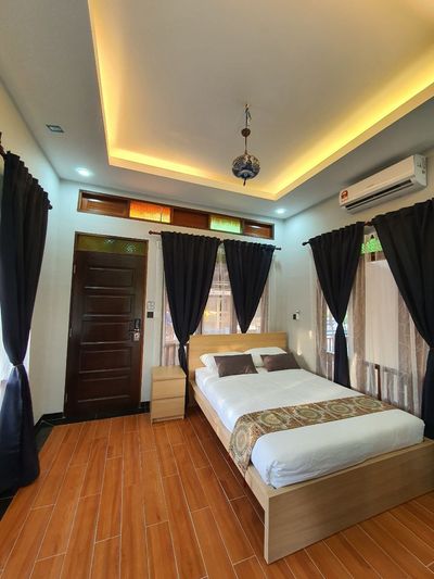 Bilik berlantai kayu dengan lampu gantung dan langsir panjang.