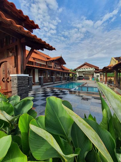 Pintu kayu dan bumbung dibingkai daun tropika
