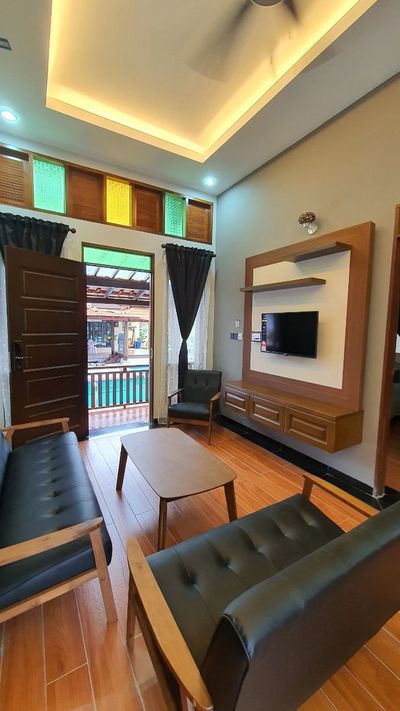 Ruang duduk dengan lantai kayu dan pintu terbuka ke arah kolam