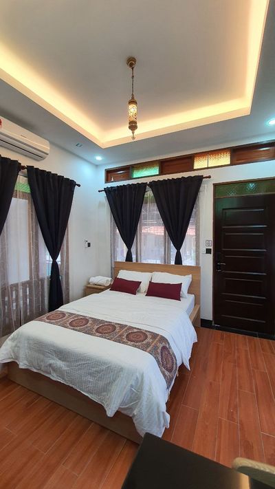 Bilik dengan katil queen, bantal merah tua dan tingkap bercahaya.